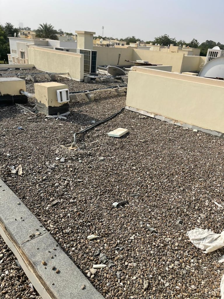 Flat rooftop with gravel surface, HVAC units, and cream-colored parapet walls