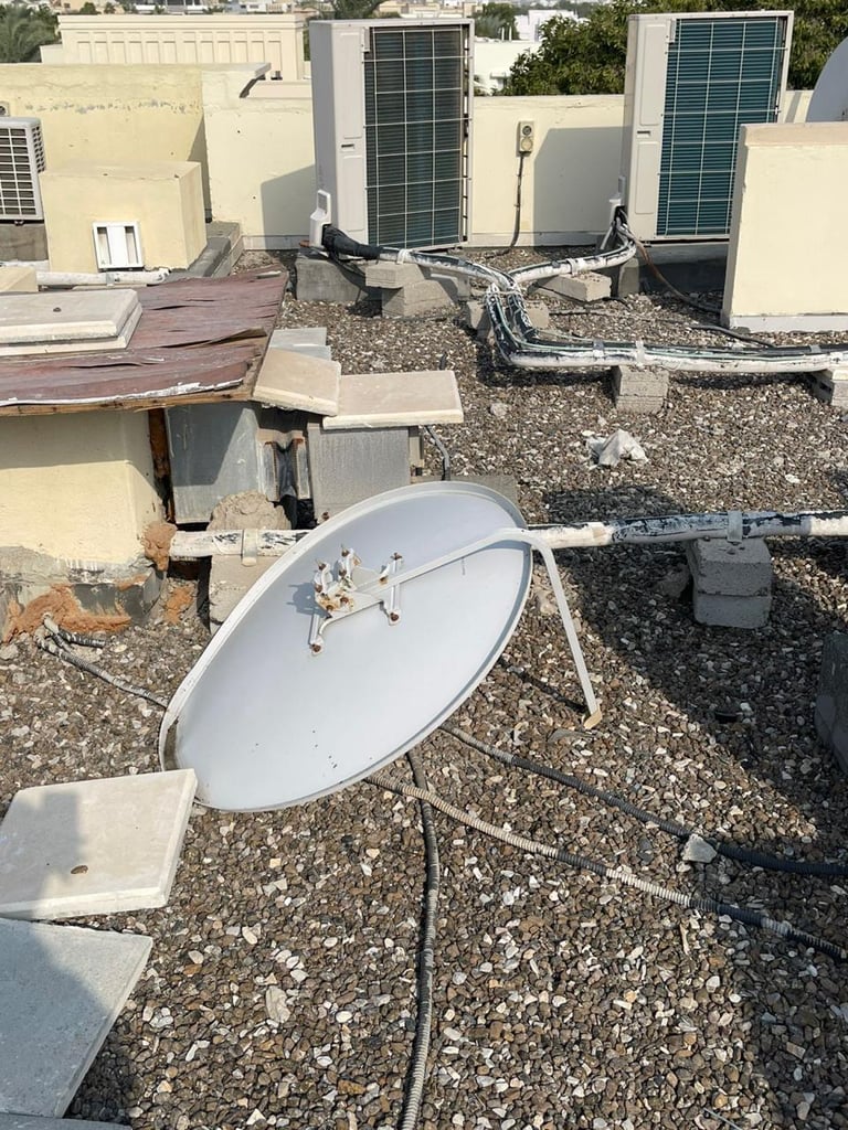 Rooftop with satellite dish and HVAC equipment on gravel surface next to cream-colored mechanical units